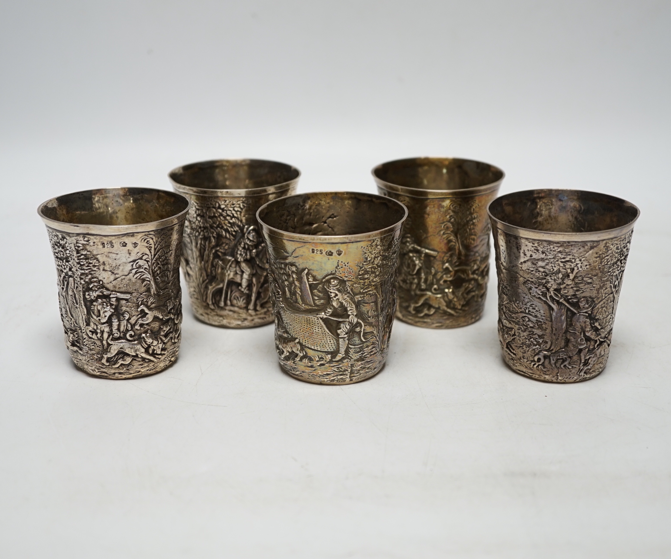A set of five late 19th century German embossed 925 beakers, decorated with continuous hunting scenes, by Neresheimer Ludwig & Co, 67mm, 16.7oz